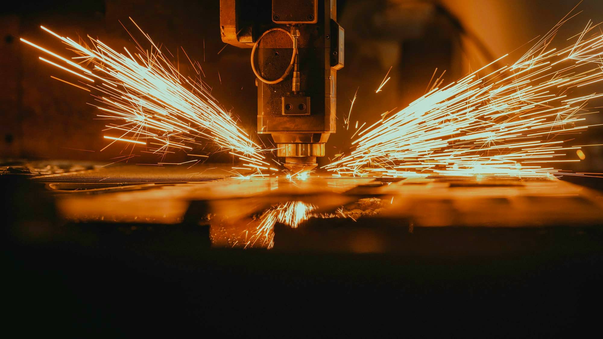Sparks flying from a CNC cutting head as it cuts sheet metal