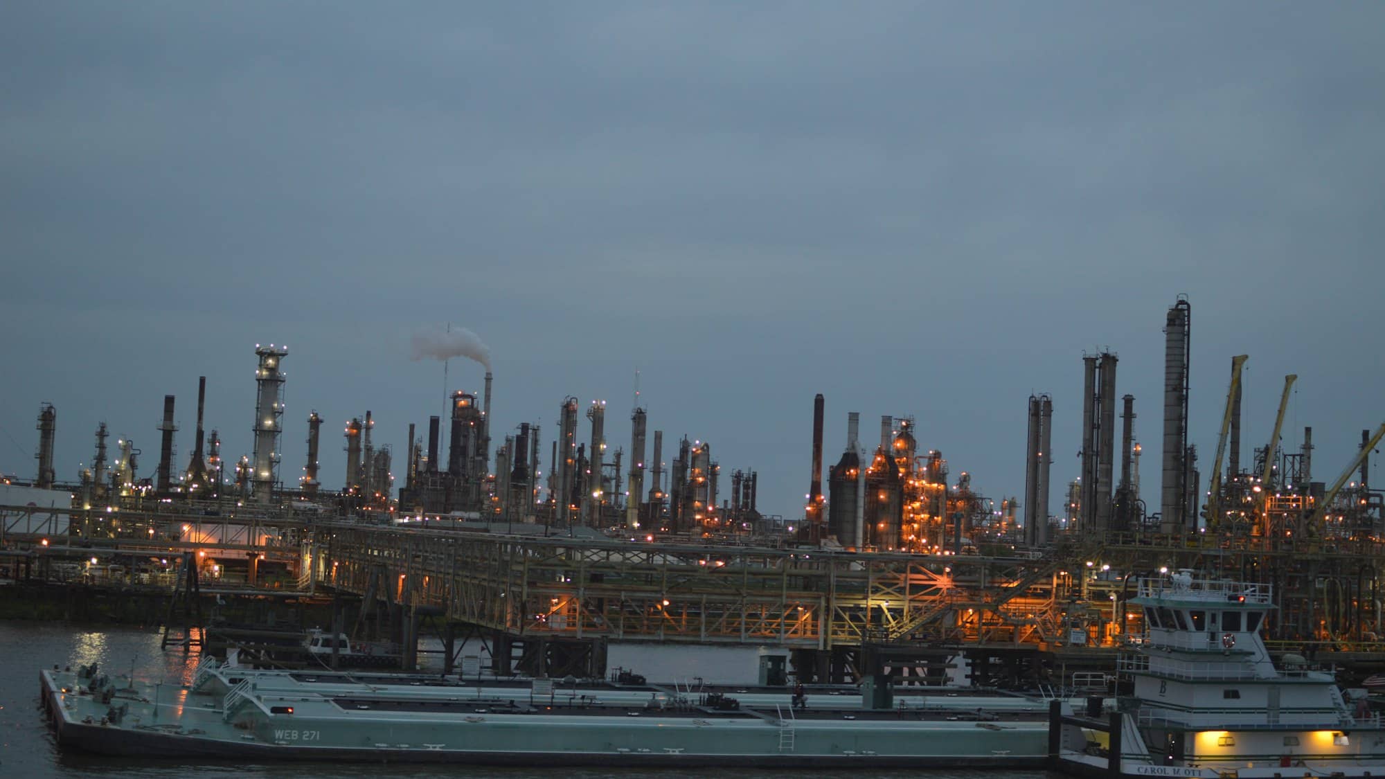 A refinery lit at dusk, seen across the water