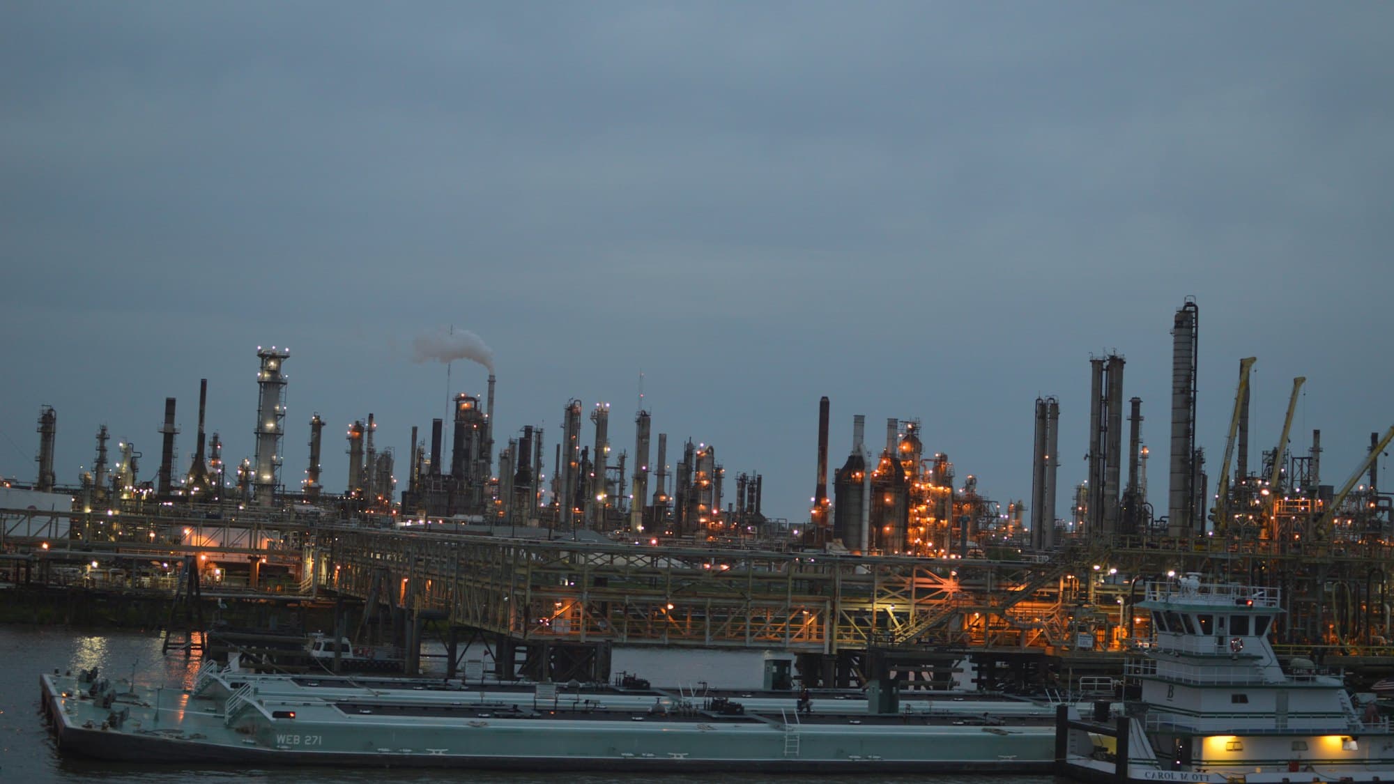 A refinery lit at dusk, seen across the water