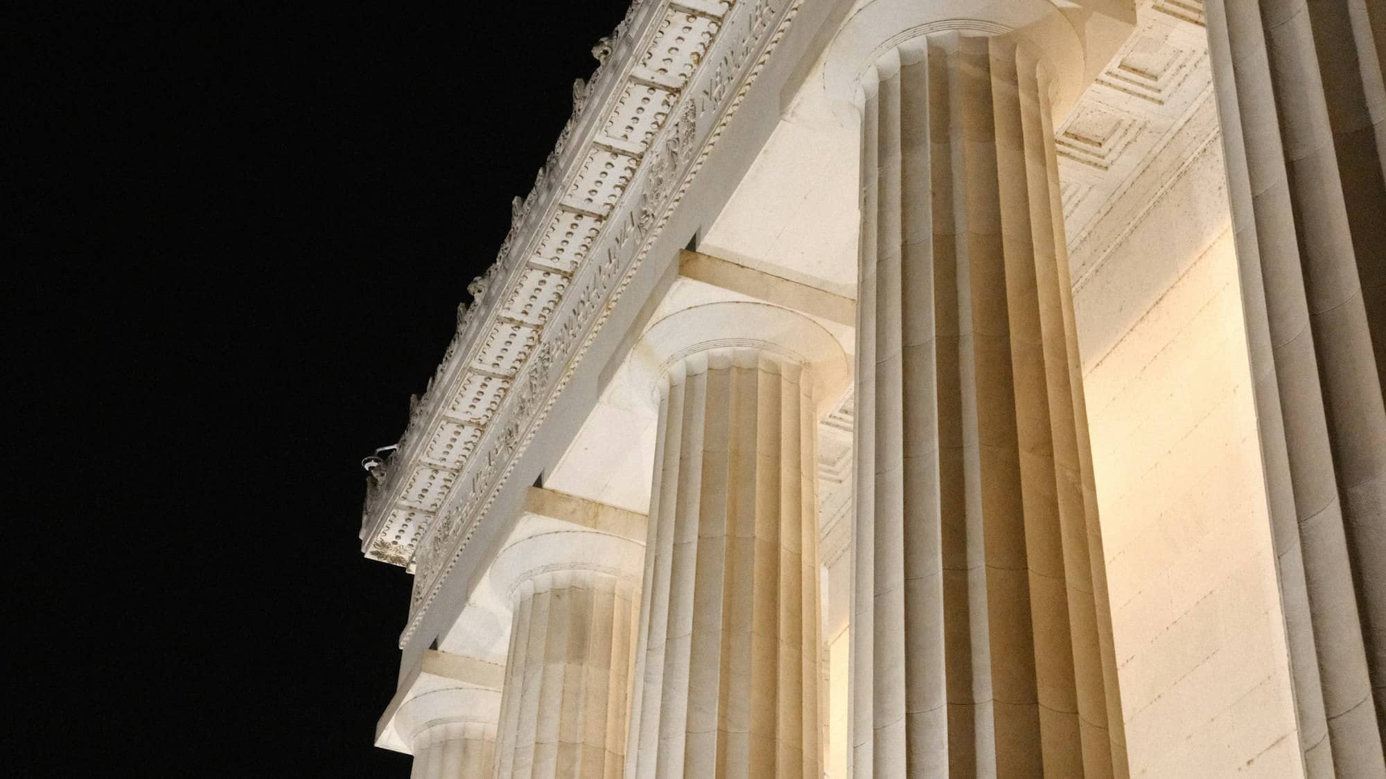 Classical stone columns lit at night against a black sky
