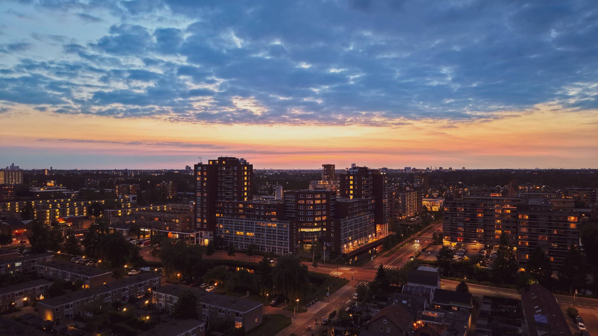 A city of apartment blocks at twilight with the lights coming on